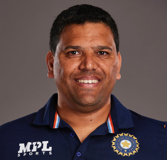 Cricket Coach wearing a navy blue polo shirt with MPL Sports and an emblem on a gray background