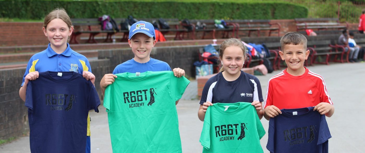 Four children holding R66T Academy t-shirts in an outdoor setting.