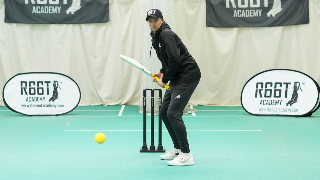 Person practicing cricket batting in an indoor facility with 'R66T Academy' branding.