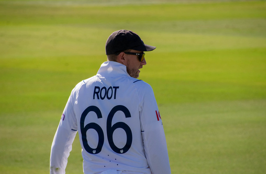 Joe Root, England player, in white uniform with 'Root' and '66' on the field.