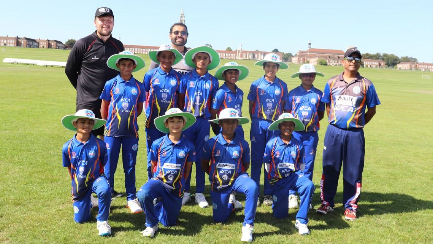 Group of cricket players and coaches posing on a grass field