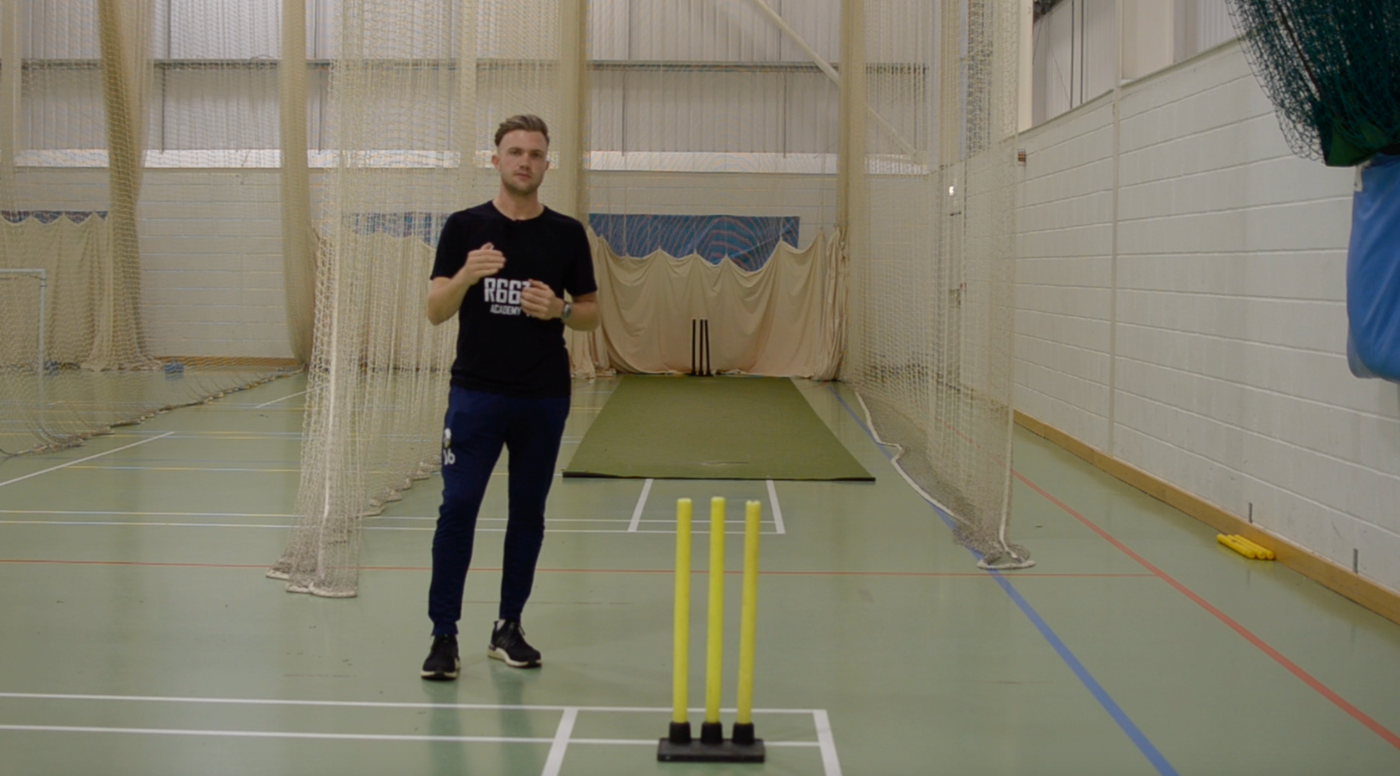 Man in a sports facility preparing to bowl in cricket practice