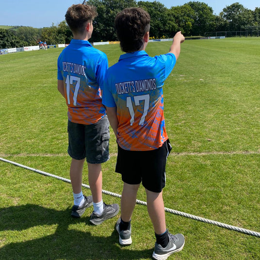 Two boys in blue sports jerseys with 'Buckett's Diamonds' and number '17' on a grass field.