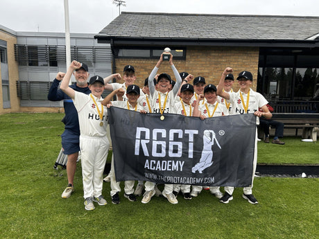 Young cricket team wearing medals, holding a winning trophy, and holding a 'R66T Academy' flag