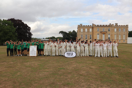 Young cricket teams stood together on a field with a castle in the background at the State School League Tournament