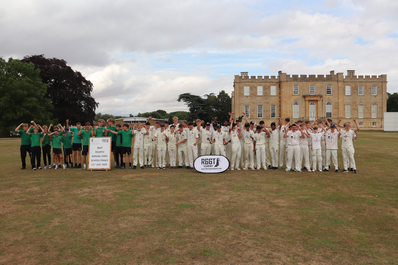 Young cricket teams stood together on a field with a castle in the background