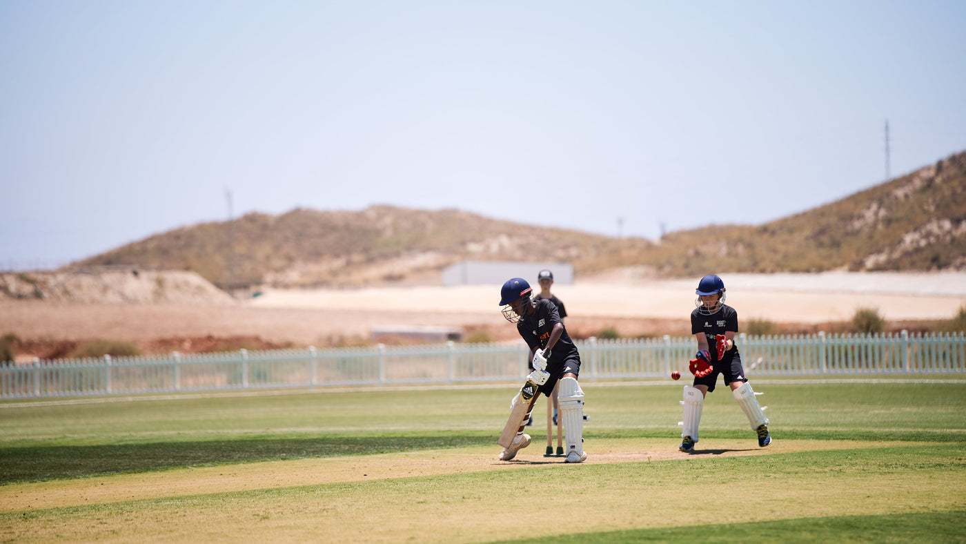 Two cricket players on a field in Desert Springs, Spain