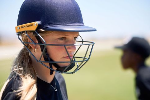 Person wearing a cricket helmet with 'MASURI' branding on a blurred outdoor background