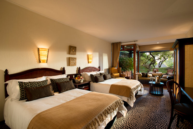 Luxurious bedroom with two beds, decorative pillows, and a large window.