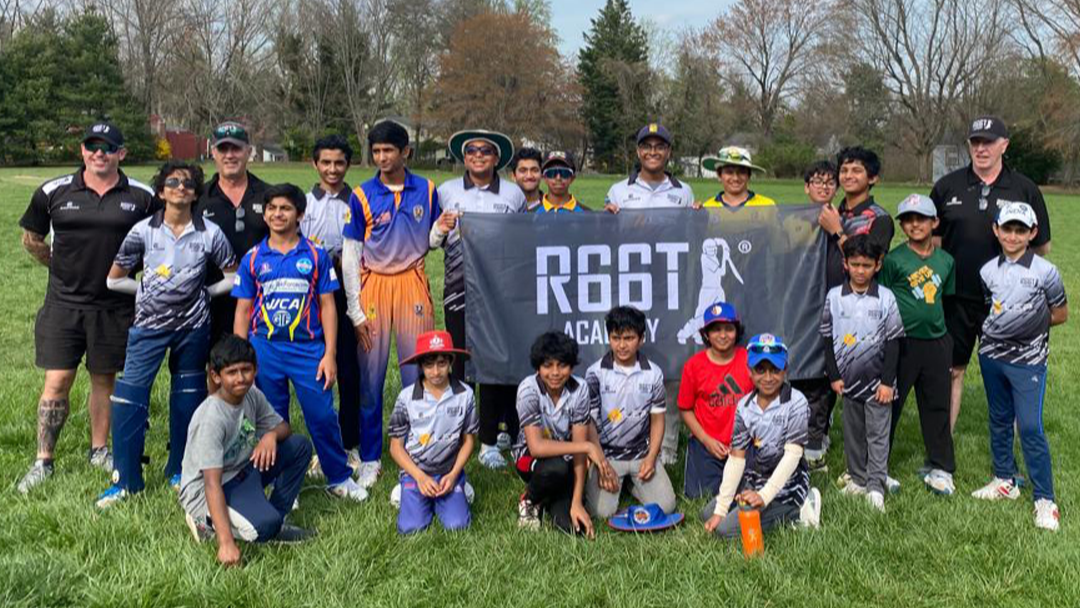 Group of children and adults posing with a banner on a grassy field