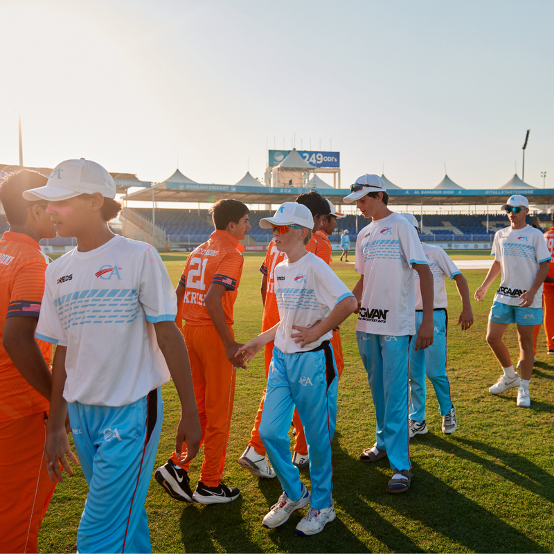 Two cricket teams shaking hands after a match at a stadium