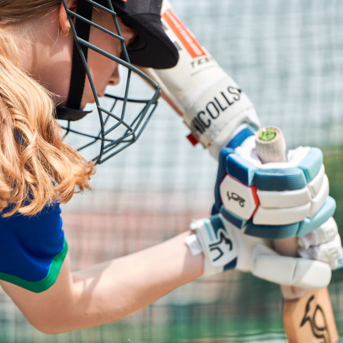 Girl holding a cricket bat in outdoor nets at Dubai