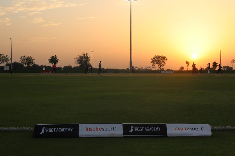 Sunset over a sports field with silhouettes of people and 'inspiresport' and 'R66T Academy' branding.