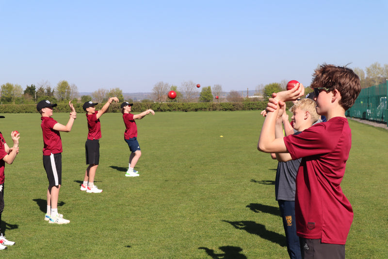 Children practicing throwing balls on a grassy field