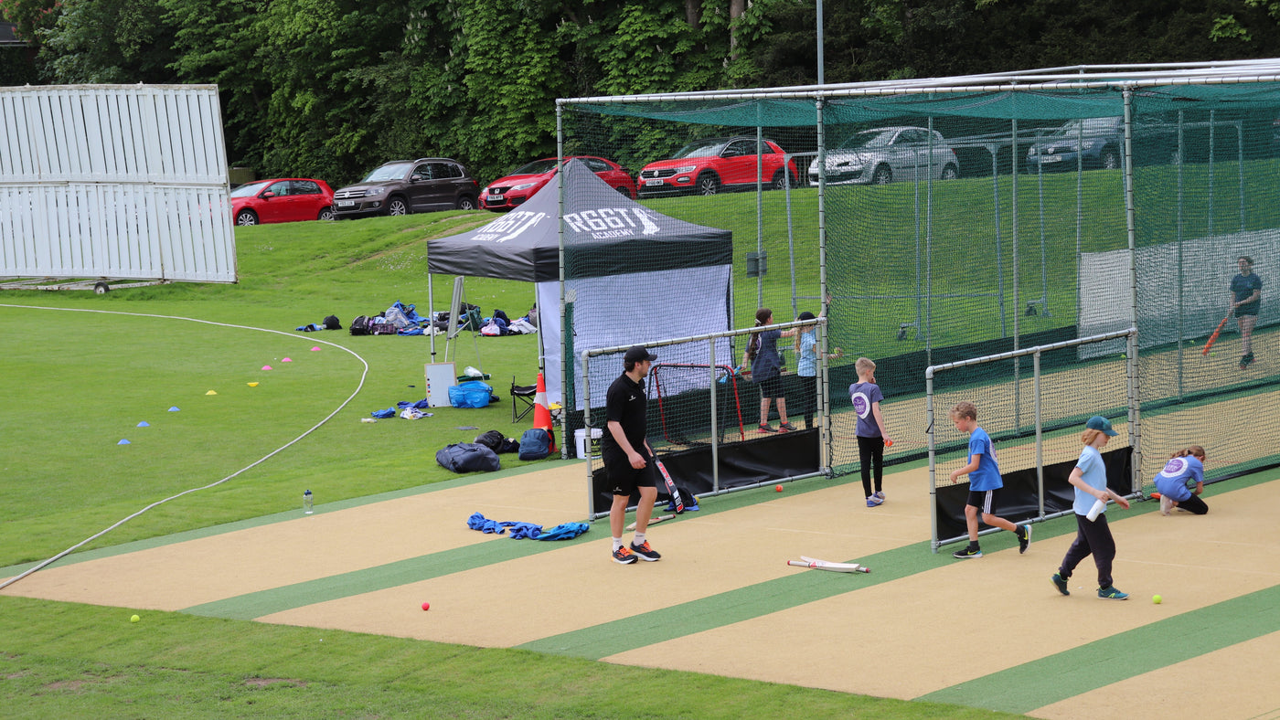 Cricket coaching session with young players outdoors in the nets
