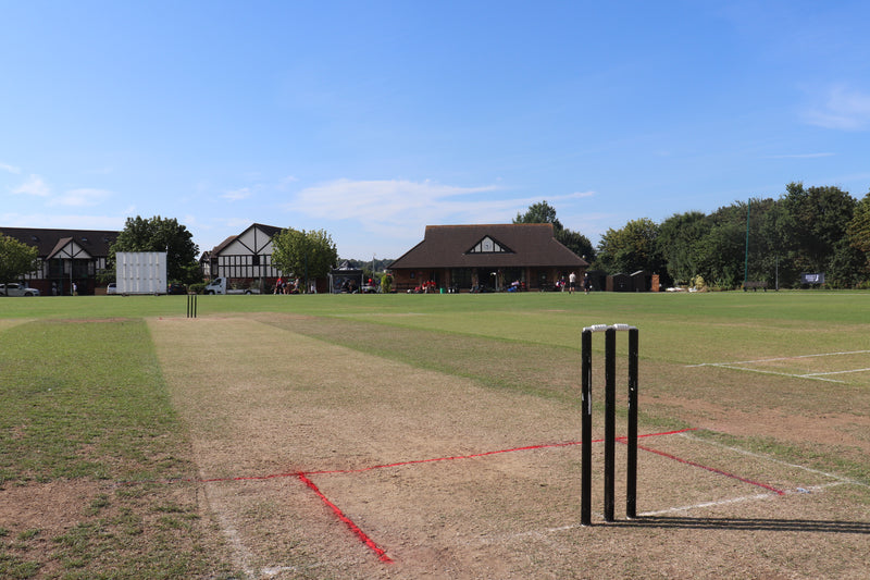 Bishopston cricket club pitch with wickets and boundary lines on a sunny day.