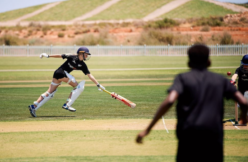 Person playing cricket on a grass field with a blurred background