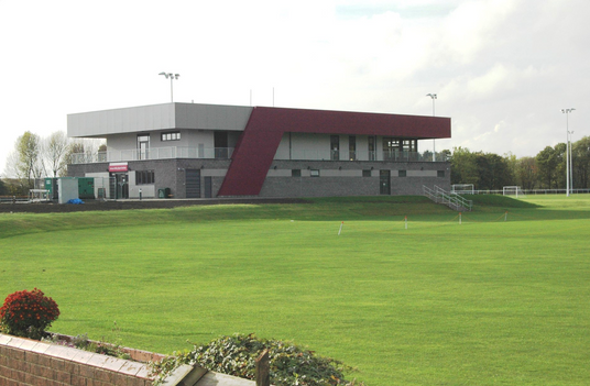 Green sports field with a modern cricket pavillion