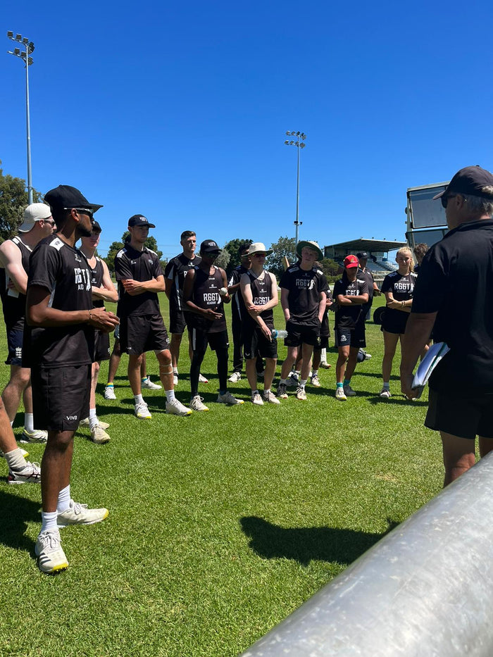 Group of athletes and coaches on a sports field with clear blue sky
